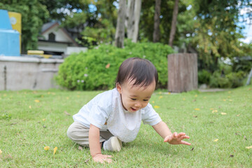 Asian toddler boy having fun on the grass at playground