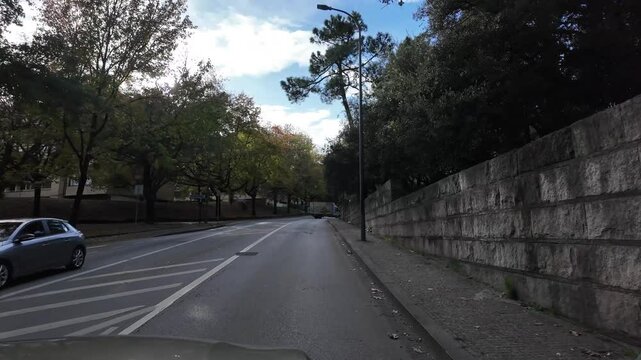  ruas do Porto, com cal&ccedil;adas de pedra e edif&iacute;cios hist&oacute;ricos alinhados em ambos os lados. Um carro moderno est&aacute; em movimento, capturado no ato de conduzir pelas vias estreitas e sinuosas da cidade. As