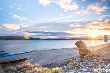 Sonnenuntergang in Allensbach am Ufer des Gnadensees mit Baumstumpf und Boot im Vordergrund – Ein...