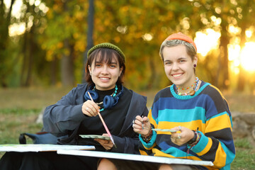 two young and innovative female artists conducting an outdoor painting lesson. Surrounded by...