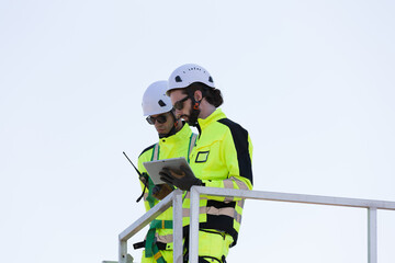 Group of male engineer working with plan inspecting or maintenance of wind turbines at windmill...