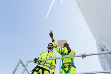 Group of male engineer working with plan inspecting or maintenance of wind turbines at windmill...