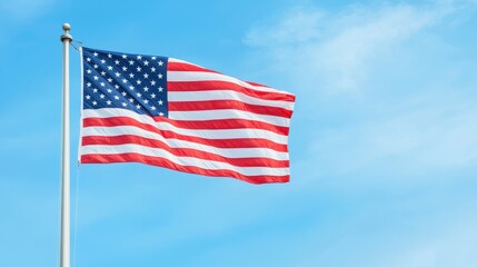 Fototapeta premium The american flag flutters under a clear blue sky, symbolizing freedom and patriotism