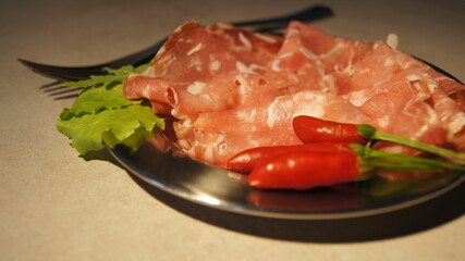 Meat platter, snacks for the table, dry-cured beef, salami, traditional Italian cold cuts, meat portion for one person, with chili pepper and lettuce leaves, food decor, on a silver platter