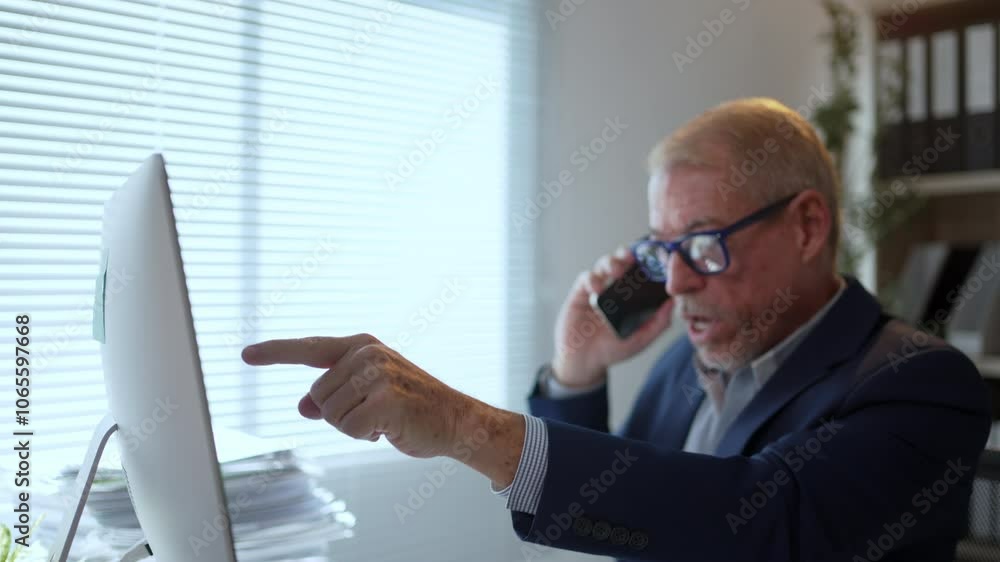 Poster Businessman sitting at a desk, talking on the phone while pointing at a computer screen during a work related discussion