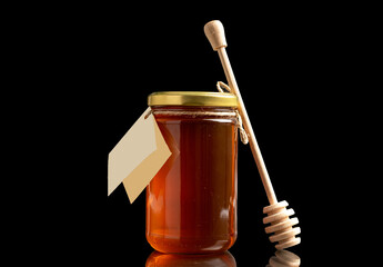 One glass jar with sweet honey, macro, isolated on black background.