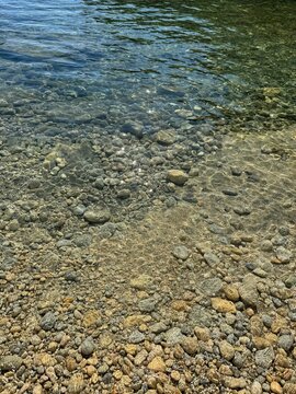 Clear sea with smooth pebbles, shingles, stones.