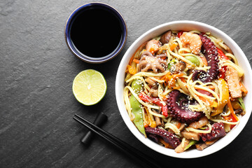 Stir-fry noodles with sea food served on grey textured table, flat lay