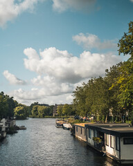 Fototapeta premium Houseboats Along a Canal Under a Cloudy Sky in Amsterdam