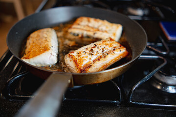 Three fish fillets searing in metal pan 