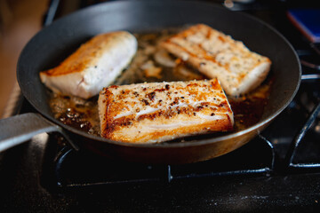 Searing fish in metal pan on stove 