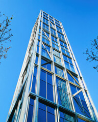 Low-angle view of a modern glass building showcasing geometric steel structure against a clear sky
