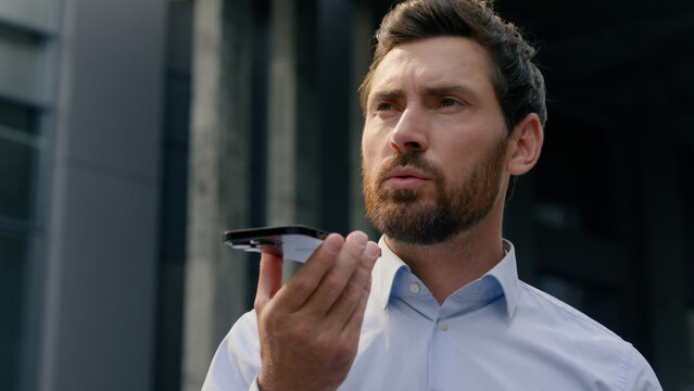 Smartphone talking microphone loudspeaker dictate to mic translation Caucasian businessman employer middle-aged man record audio message voice mail business male adult guy in city talk mobile phone