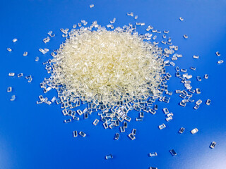 Transparent polycarbonate plastic granules on a blue background, one of the basic materials in the...