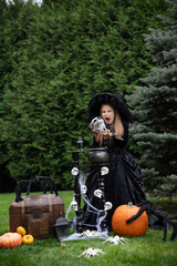 Witch Sorceress Girl Conjures Skull With Her Mouth Open On Halloween Against The Background Of Herb Potion