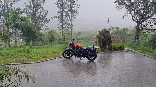 A wide view of a superbike parked outside a house in heavy rain at a hill station in Karnataka