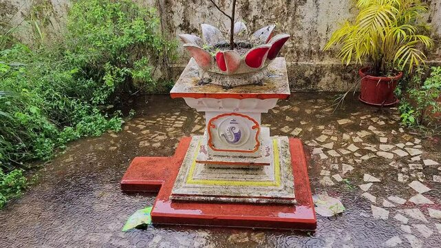 A video of a holy basil pot or tulsi temple in front of an Indian house on a rainy day