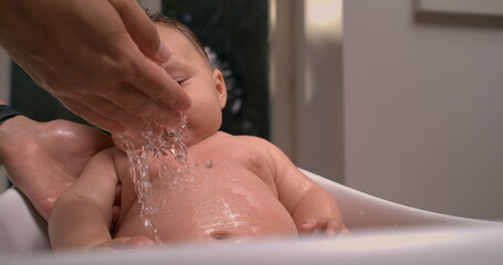 Water pouring over baby&rsquo;s chest during bath, baby smiling and looking up calmly, relaxing and peaceful bath care moment. 800 fps slow-motion