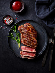 Beef Steak medium rare with French fries on a black plate. Dark background. Top view.