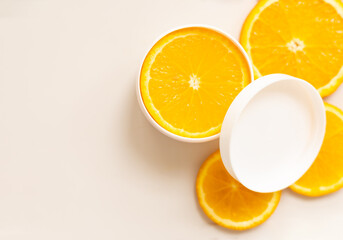 facial cream with vitamin C, slice of orange, packaging container, copy space