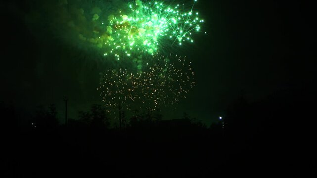 gold lilac blue green sparks scattering fireworks on the black night sky over the city. General plan