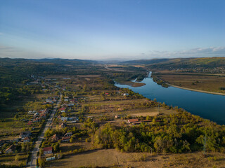 Naklejka premium Rural landscape viewed from the drone. A village in Romania located on the edge of a lake near the wild forest