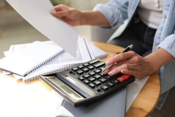 Budget planning. Woman using calculator while working with accounting document at table indoors,...