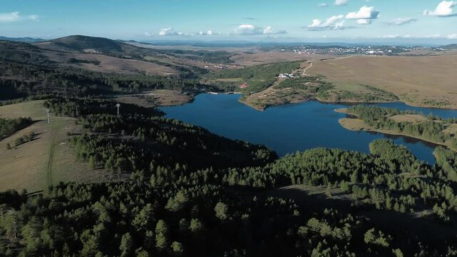 Nature of western Serbia in early autumn on a sunny warm day. Aerial sunset view from a drone of Lake Ribnichko in Zlatibor national park, next to the cable car leading to Mount Tornik