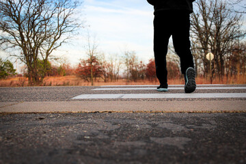 low angle shot of man crossing pedestrian crosswalk in the evening