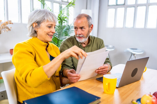 Senior couple looking at financial bills using laptop - Powered by Adobe