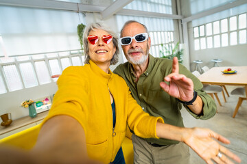 Senior woman with heart shape sunglasses taking selfie with husband