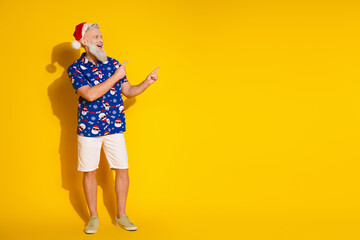 Full body portrait of stylish santa direct fingers empty space new year xmas print shirt isolated on yellow color background