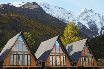 Autumn mountain tourism. Triangular chalets for tourists on the background of picturesque mountains...