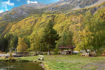 Recreation and picnic area by a pond in the mountains during the golden fall season.