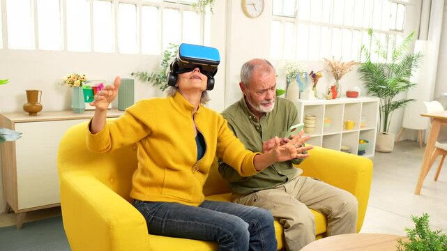Elderly couple with playing VR game together using virtual reality goggles and mobile phone