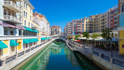 Fototapeta premium Colorful waterfront shops, cafes and residential apartments along the canals in the Venetian inspired Qanat Quartier, on the manmade artificial Pearl Island, Qatar.