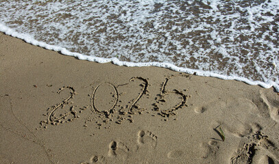 tropical New Year 2025 written in sand on the beach