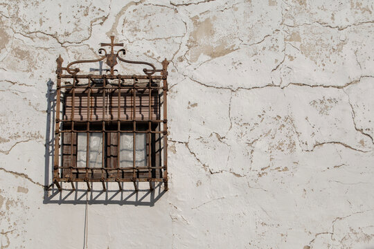 Window with typical La Mancha grille on a peeling and old facade