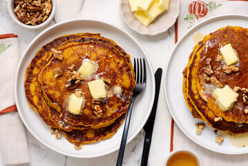Pumpkin pancakes with butter, maple syrup and walnuts on a plate