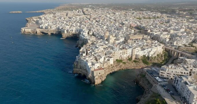 Aerial view at sunset of the historic center of Polignano a Mare, in the province of Bari, Puglia, Italy. In the middle of the Old Town there is the Mother Church of Santa Maria Assunta.
