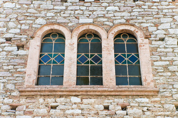 Finestra trifora con vetrate colorate in stile antico su facciata in pietra