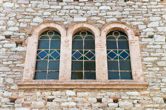 Finestra trifora con vetrate colorate in stile antico su facciata in pietra
