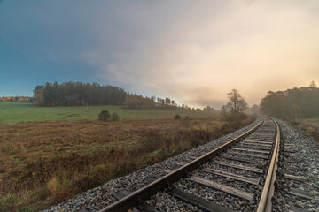 Obraz premium Railway track for engine unit passenger trains in autumn foggy morning