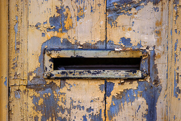 Closeup image of a weathered, peeling paint on an old wooden door with a vintage mail slot, perfect...