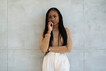 A poised black businesswoman stands in a sleek office setting, dressed professionally, phone in...