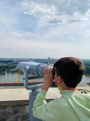 Young boy looking through telescope at panoramic Bratislava city view