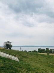 Tranquil lakeside landscape with grassy hills and cloudy sky