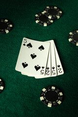 A group of friends engages in a spirited poker game under dim lighting, focusing on their cards and strategy while colorful chips surround them on the plush green felt table