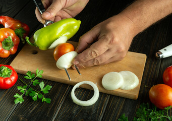 A skilled cook meticulously slices vibrant peppers, onions, and tomatoes on a cutting board. Fresh...