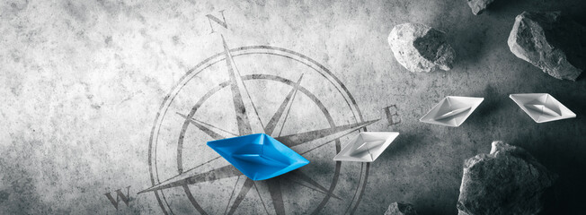 Blue Paper Boat Leading A Fleet Of Small White Boats Away From Rocks With Compass Icon - Leadership Concept